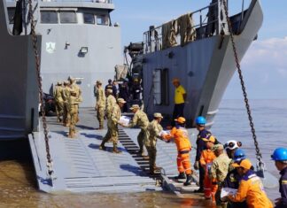 En un esfuerzo mancomunado entre la Armada de Colombia y la Gobernación de La Guajira, en articulación con el Programa Mundial de Alimentos (PMA), el Ejército Nacional, la Policía Nacional, la Cruz Roja Colombiana, la Defensa Civil, el ICBF, entre otras organizaciones, inició hoy la entrega de ayudas en el departamento de La Guajira, afectado por la segunda temporada de lluvias que azota al país en los últimos días. A primeras horas de la mañana emplayó en el sector conocido como “Amas Sai”, en Riohacha, el Buque de Desembarco Anfibio ARC “Golfo de Urabá” para iniciar el embarque de las ayudas que fueron dispuestas, con el fin de brindar asistencia humanitaria a las comunidades afectadas en la Alta Guajira, las cuales permanecen incomunicadas debido a las graves inundaciones de la región. A bordo del ARC “Golfo de Urabá” y de los camiones de Infantería de Marina de la Armada Nacional, que llegarán a siete puntos nodales de la Alta Guajira enfrentando condiciones adversas de tiempo y terreno, se transportarán más de 150 toneladas de elementos de primera necesidad y víveres, entre los que se encuentran alimentos, kits de aseo, agua potable, entre otros. Jairo Aguilar Deluque, gobernador de La Guajira, destacó la importancia de esta operación, señalando que “la unión de esfuerzos entre las instituciones y organizaciones permite atender de manera oportuna a quienes más lo necesitan, llevando esperanza a las comunidades afectadas”. En Riohacha fueron entregadas 2.7 toneladas de arroz gestionadas por la Armada de Colombia ante la Corporación “Minuto de Dios”, para iniciar la atención a los afectados de este municipio. Durante 15 días, el ARC “Golfo de Urabá” y los vehículos del Batallón de Movilidad de Infantería de Marina tendrán la misión de transportar y entregar ayudas humanitarias en Bahía Honda, Bahía Hondita, Castilletes, Karasúa, Puerto Bolívar, Puerto Estrella y Puerto López, con apoyo de 71 integrantes de las diferentes autoridades y entidades. Cabe resaltar que la Institución Naval desde la declaratoria de emergencia realizada por el Gobierno Nacional el pasado domingo 10 de noviembre, se encuentra desplegada con sus capacidades de empleo dual y su equipo humano para brindar apoyo humanitario y asistencia a la autoridad civil, en las comunidades del Caribe que han sido afectadas por este fenómeno. La Armada de Colombia, a través de la Fuerza Naval del Caribe, reitera su compromiso de contribuir a la consolidación territorial y al mejoramiento de la calidad de vida de los habitantes de la región, trabajando de manera articulada con entidades públicas y privadas.