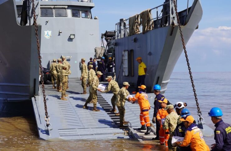 En un esfuerzo mancomunado entre la Armada de Colombia y la Gobernación de La Guajira, en articulación con el Programa Mundial de Alimentos (PMA), el Ejército Nacional, la Policía Nacional, la Cruz Roja Colombiana, la Defensa Civil, el ICBF, entre otras organizaciones, inició hoy la entrega de ayudas en el departamento de La Guajira, afectado por la segunda temporada de lluvias que azota al país en los últimos días. A primeras horas de la mañana emplayó en el sector conocido como “Amas Sai”, en Riohacha, el Buque de Desembarco Anfibio ARC “Golfo de Urabá” para iniciar el embarque de las ayudas que fueron dispuestas, con el fin de brindar asistencia humanitaria a las comunidades afectadas en la Alta Guajira, las cuales permanecen incomunicadas debido a las graves inundaciones de la región. A bordo del ARC “Golfo de Urabá” y de los camiones de Infantería de Marina de la Armada Nacional, que llegarán a siete puntos nodales de la Alta Guajira enfrentando condiciones adversas de tiempo y terreno, se transportarán más de 150 toneladas de elementos de primera necesidad y víveres, entre los que se encuentran alimentos, kits de aseo, agua potable, entre otros. Jairo Aguilar Deluque, gobernador de La Guajira, destacó la importancia de esta operación, señalando que “la unión de esfuerzos entre las instituciones y organizaciones permite atender de manera oportuna a quienes más lo necesitan, llevando esperanza a las comunidades afectadas”. En Riohacha fueron entregadas 2.7 toneladas de arroz gestionadas por la Armada de Colombia ante la Corporación “Minuto de Dios”, para iniciar la atención a los afectados de este municipio. Durante 15 días, el ARC “Golfo de Urabá” y los vehículos del Batallón de Movilidad de Infantería de Marina tendrán la misión de transportar y entregar ayudas humanitarias en Bahía Honda, Bahía Hondita, Castilletes, Karasúa, Puerto Bolívar, Puerto Estrella y Puerto López, con apoyo de 71 integrantes de las diferentes autoridades y entidades. Cabe resaltar que la Institución Naval desde la declaratoria de emergencia realizada por el Gobierno Nacional el pasado domingo 10 de noviembre, se encuentra desplegada con sus capacidades de empleo dual y su equipo humano para brindar apoyo humanitario y asistencia a la autoridad civil, en las comunidades del Caribe que han sido afectadas por este fenómeno. La Armada de Colombia, a través de la Fuerza Naval del Caribe, reitera su compromiso de contribuir a la consolidación territorial y al mejoramiento de la calidad de vida de los habitantes de la región, trabajando de manera articulada con entidades públicas y privadas.